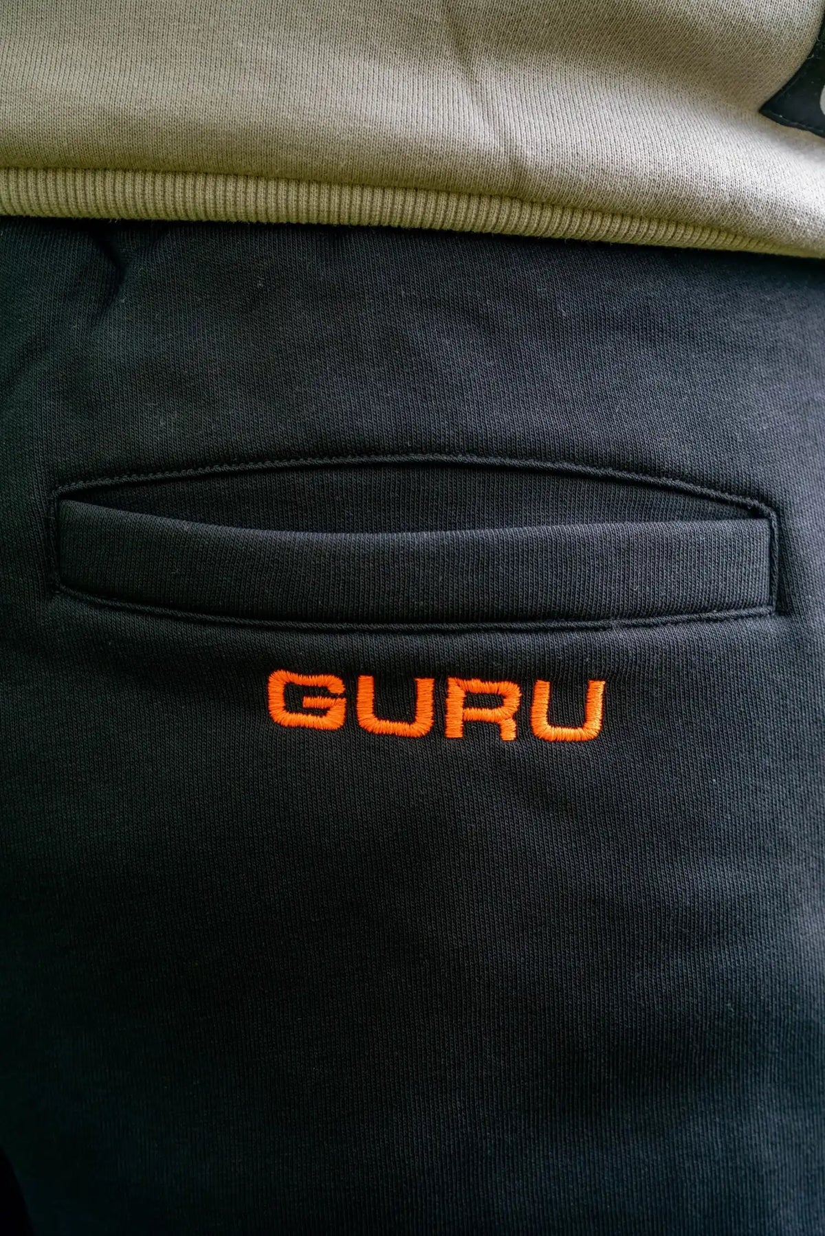 Guru Black Joggers – detail van achterzak met oranje Guru-borduurwerk