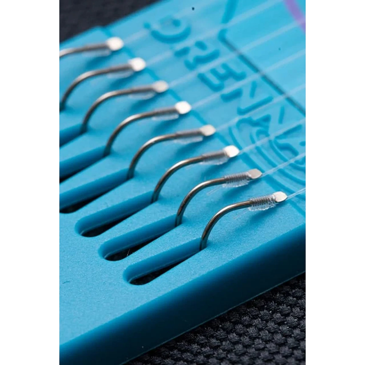 Drennan Wide Gape Carp Barbless Hooklengths – detail van acht weerhaakloze haken op blauwe Hook Plate