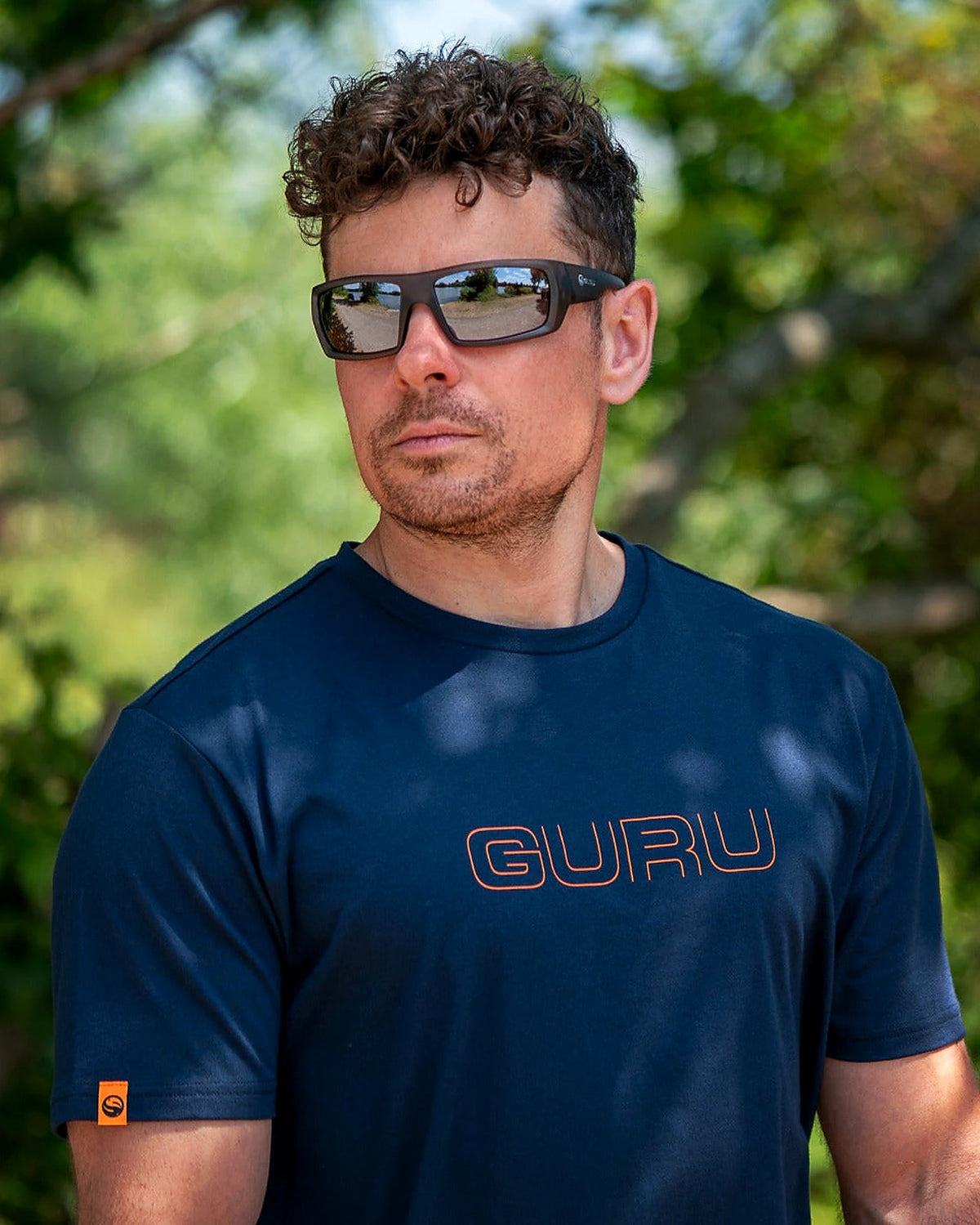 Guru Glitch Navy Tee – buitenportret van een model met het marineblauwe T-shirt en oranje Guru-logo