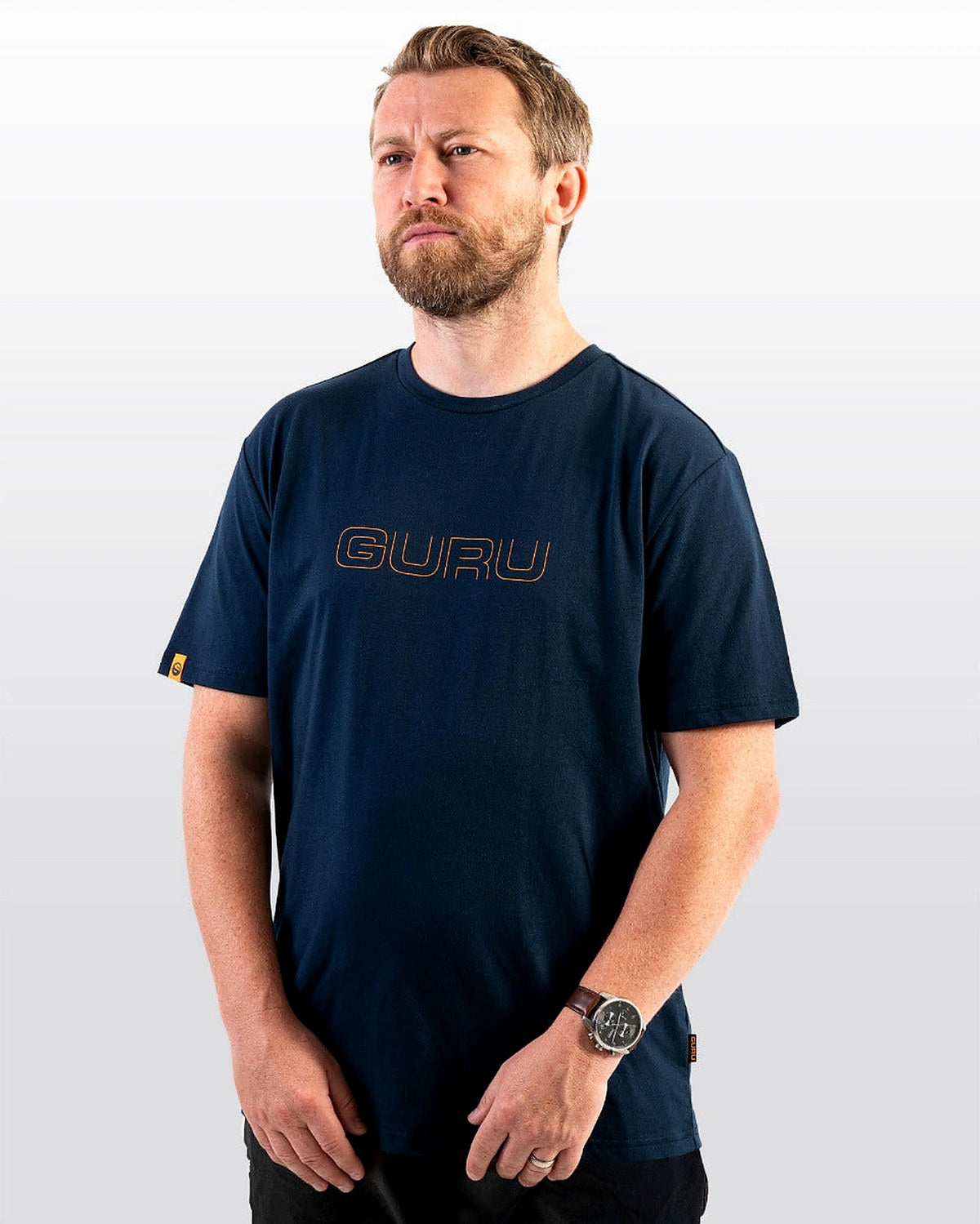 Guru Glitch Navy Tee – model draagt het marineblauwe T-shirt met oranje Guru-borstlogo