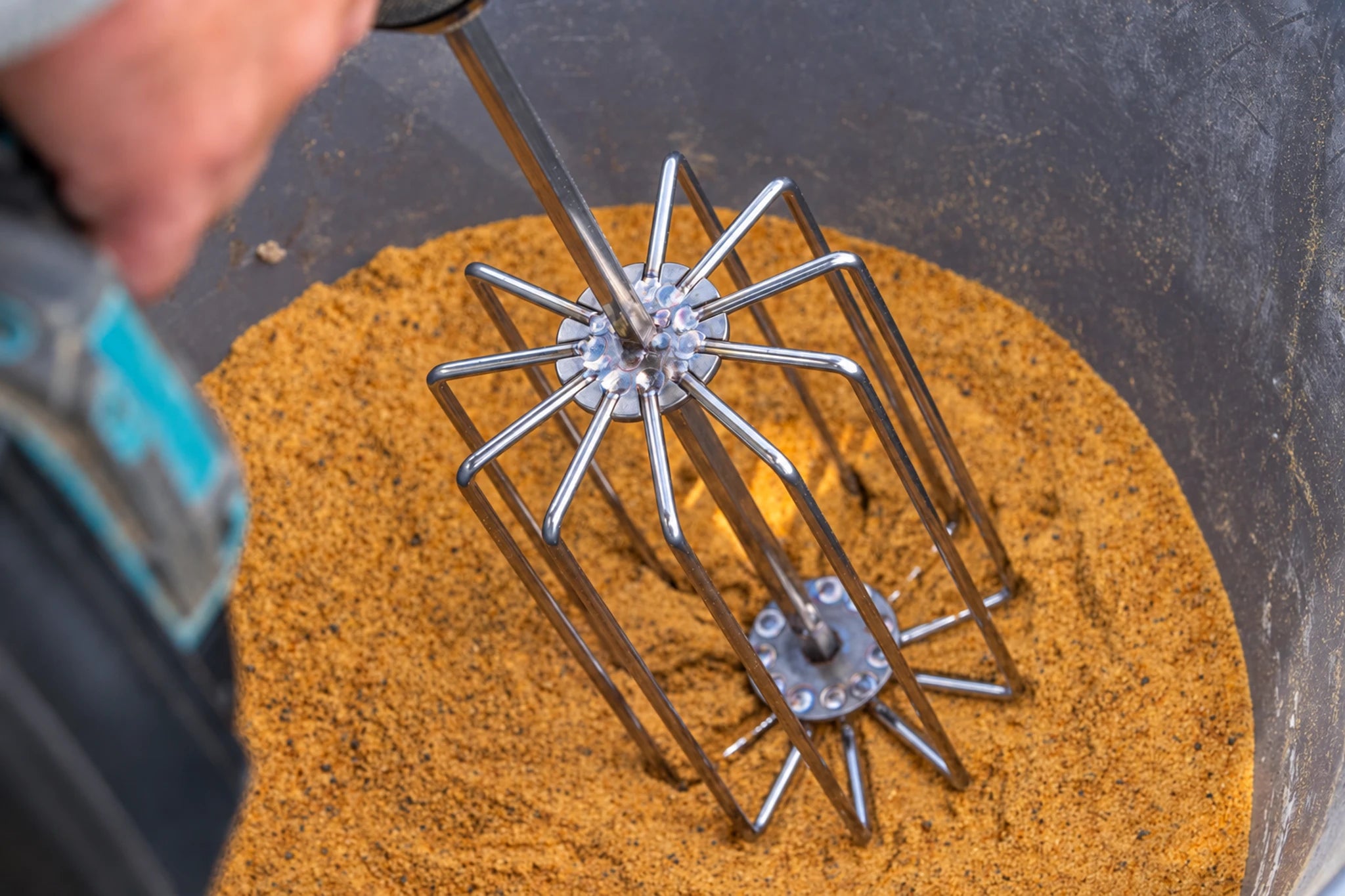 Guru Ground Bait Whisk in een emmer met grondvoer tijdens de voorbereiding