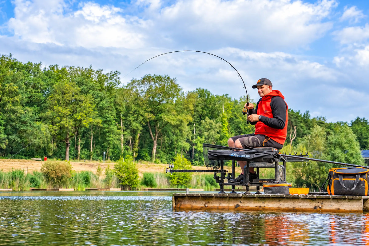 Guru N-Gauge Pro Distance Feeder – visser drilt een vis met gebogen hengel aan het water