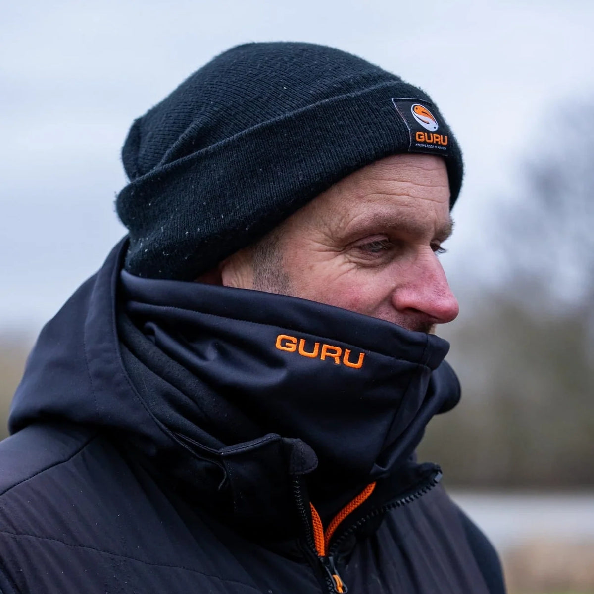 Guru Neck Warmer – visser draagt zwarte nekwarmer over mond en hals tegen koude wind