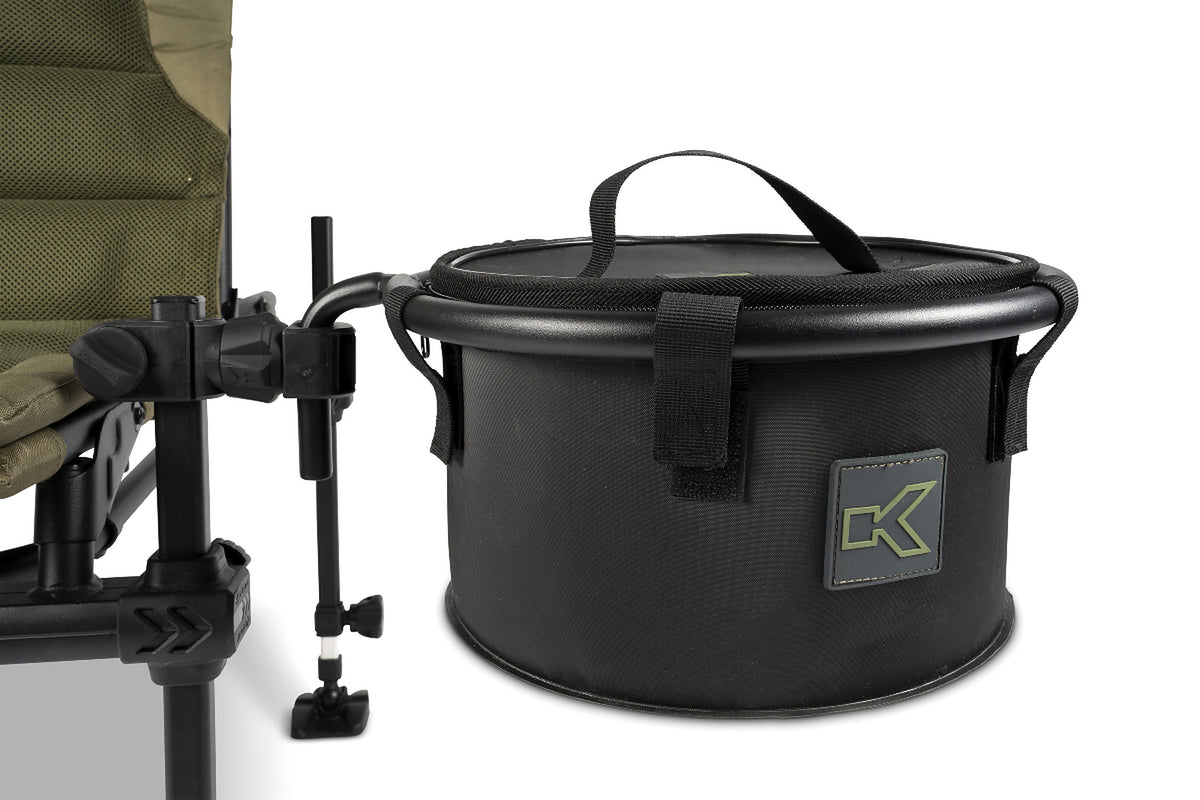 Korum Any Chair EVA Bowl & Riddle – gesloten zwarte voerbak met draaglus en Korum-logo aan een stoel gemonteerd
