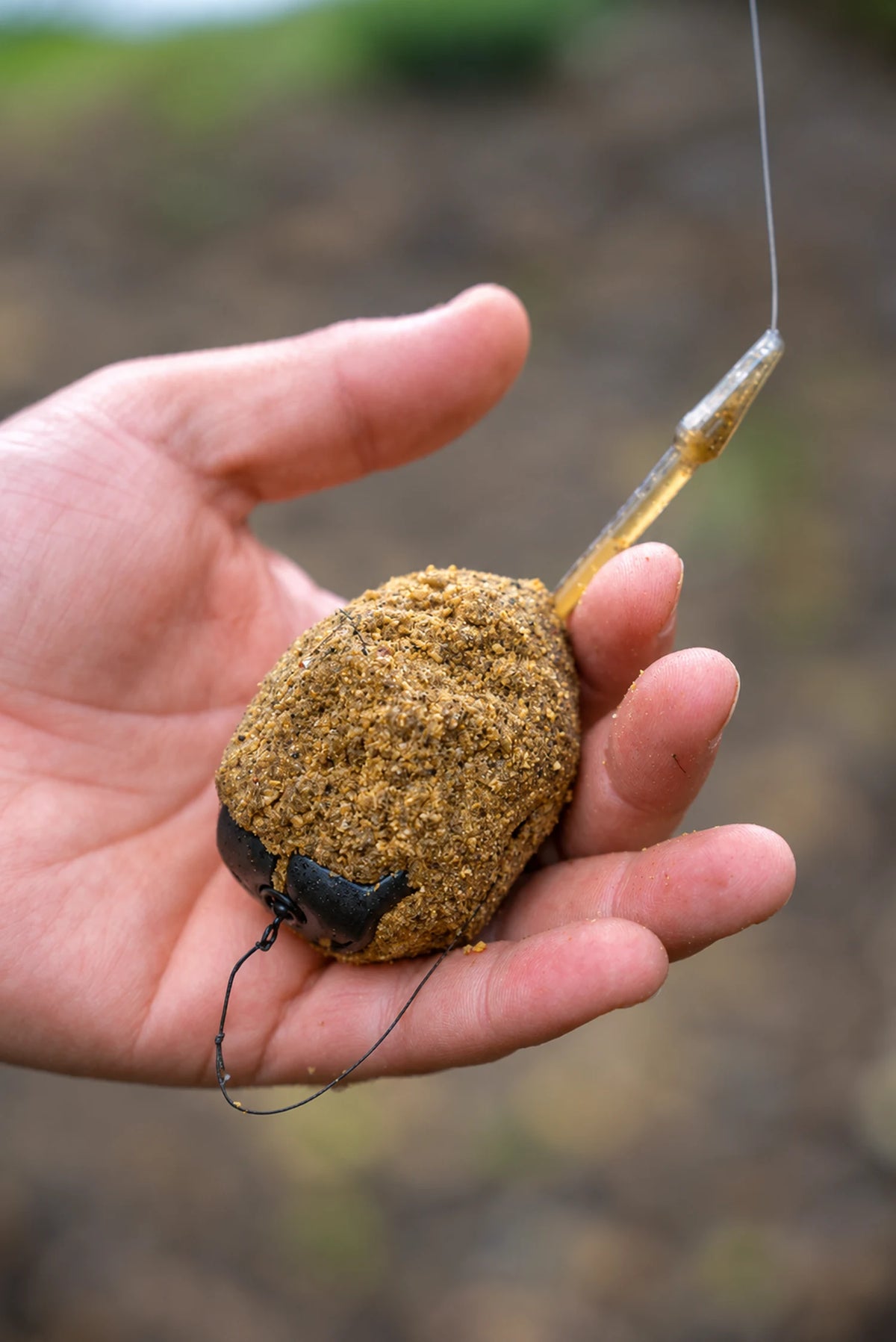 Korum Arrowhead Distance Method Feeder met grondvoer in de hand en de onderlijn eronder