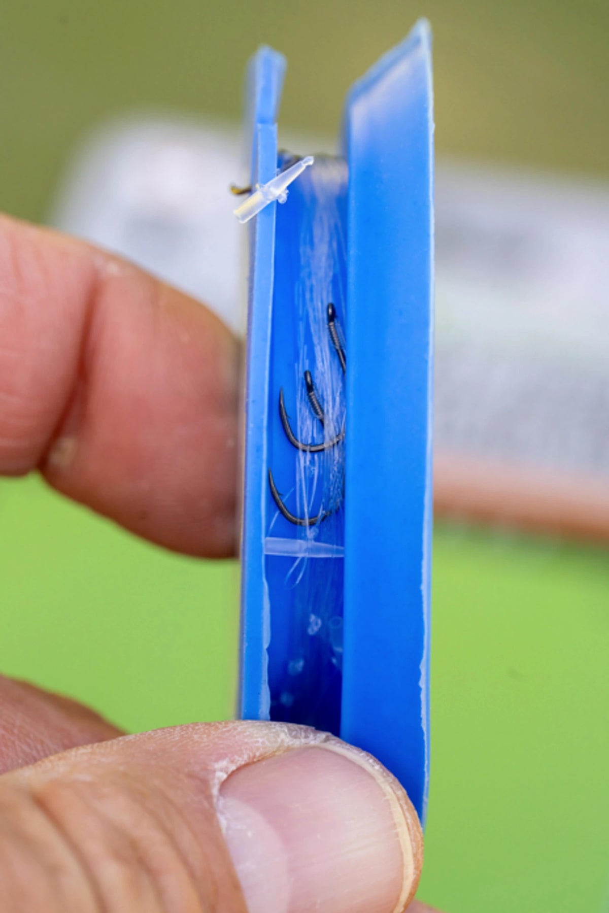 Detail van Korum Limitless onderlijnspoel in de hand, met haken, lijn en Quickstop zichtbaar