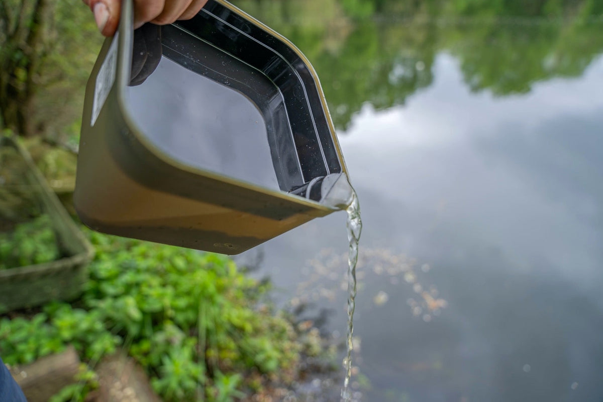 Detail van water dat langs de hoek van de Korum Method Mix aasbak met zwarte binnentray wordt afgegoten