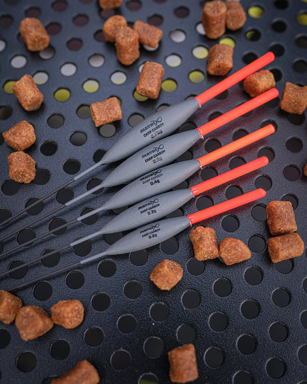 Matrix Carp Carbon Pole Floats, vijf dobbers diagonaal op een aastafel met pellets
