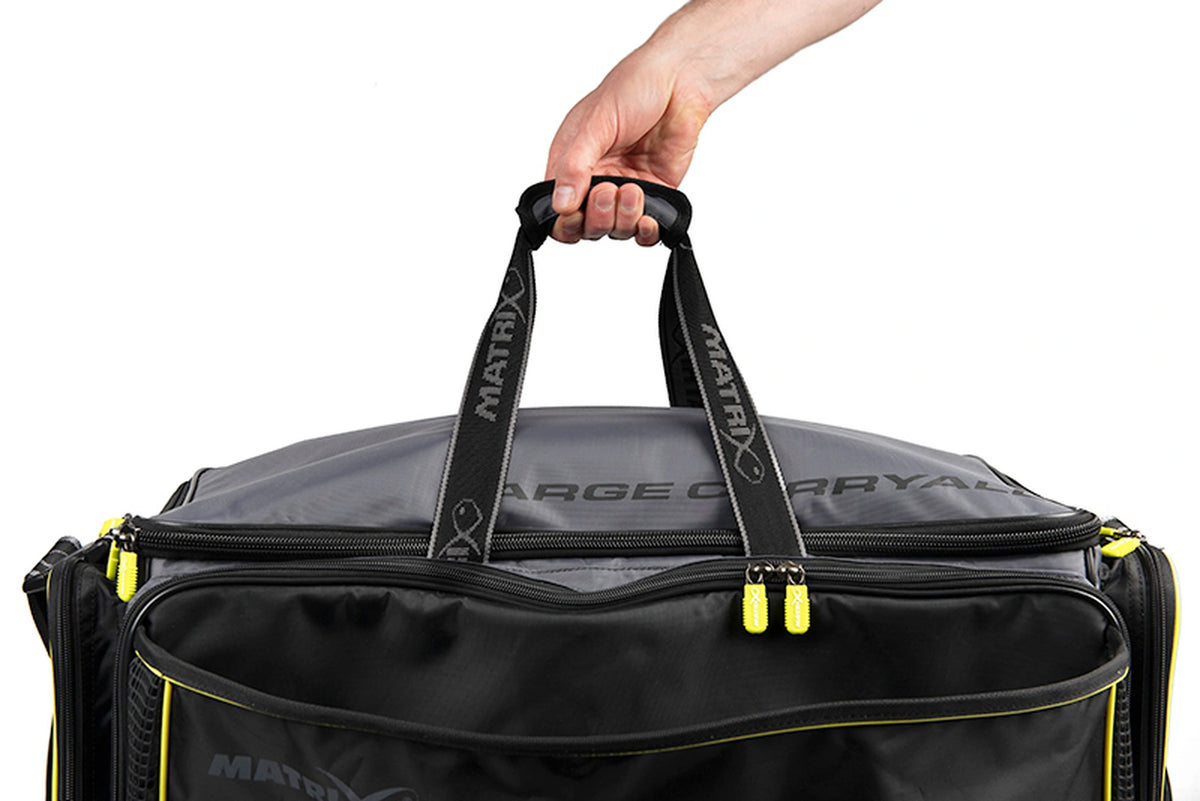 Matrix Ethos Large Carryall – hand houdt de gevoerde draaggreep vast boven de geweven Matrix-draagriemen