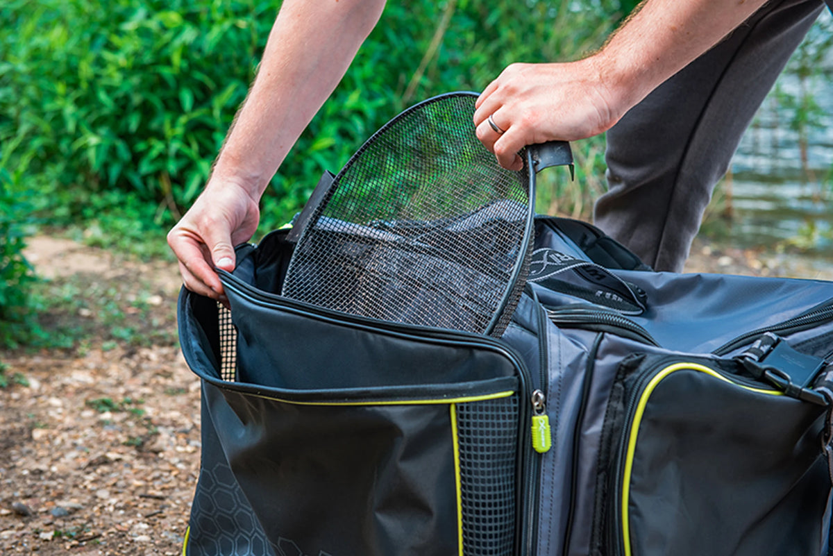Matrix Ethos Large Carryall – visser schuift een schepnet in het zwarte voorvak met gele rand en gaaszijkanten