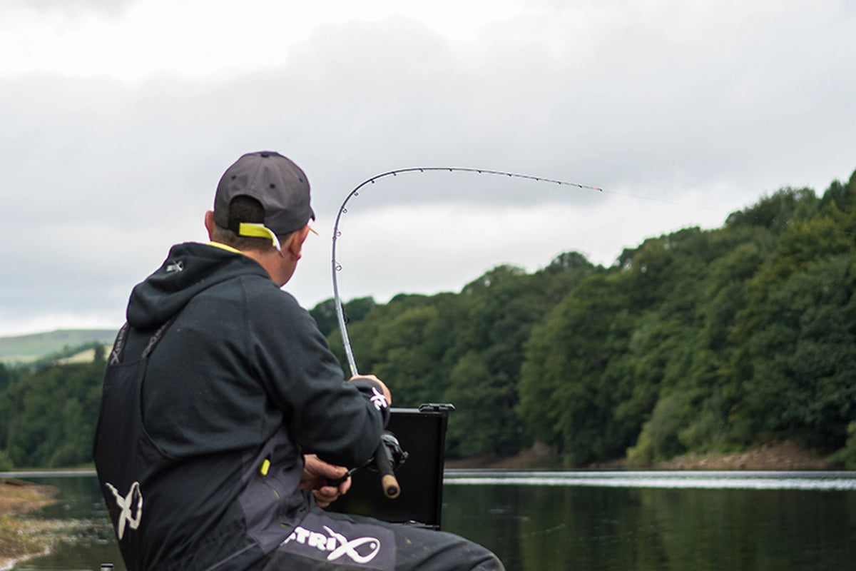 Matrix Ethos XR-S Feeder Rod in gebruik – van achteren gefotografeerde visser met een gebogen hengel aan een meer