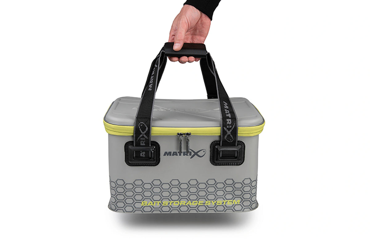 Matrix EVA Bait Storage System – hand draagt de gesloten grijze aastas aan de zwarte handgreep