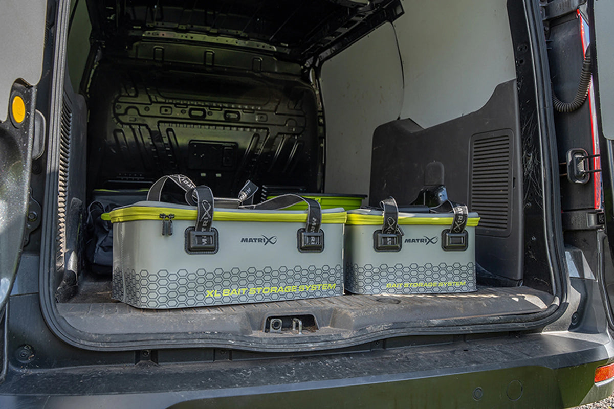 Matrix EVA Bait Storage System – de aastas rechts naast het grotere XL-model in de laadruimte van een bestelwagen