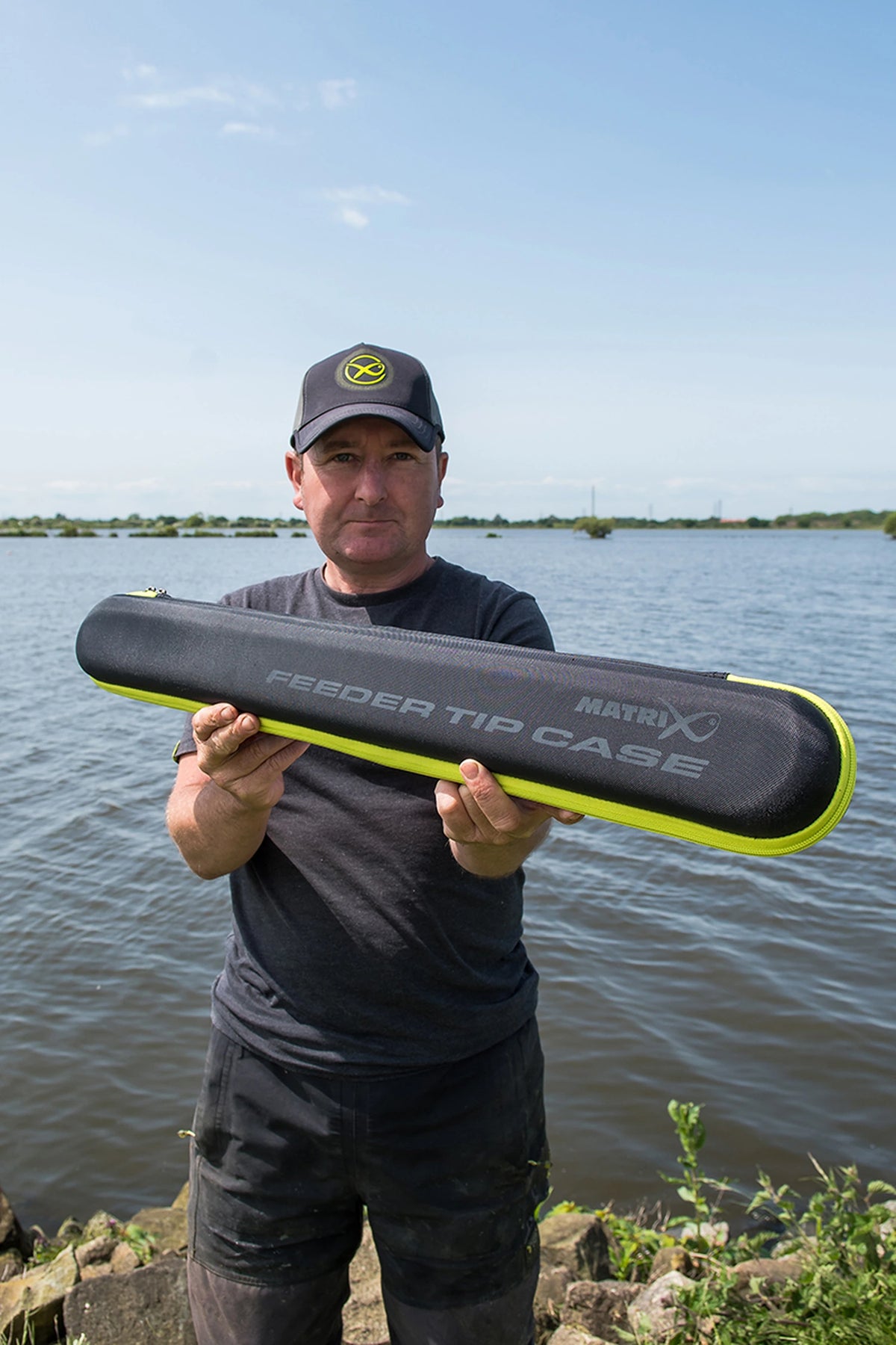 Matrix EVA Feeder Tip Case – visser toont de gesloten etui met Matrix- en Feeder Tip Case-opdruk aan het water