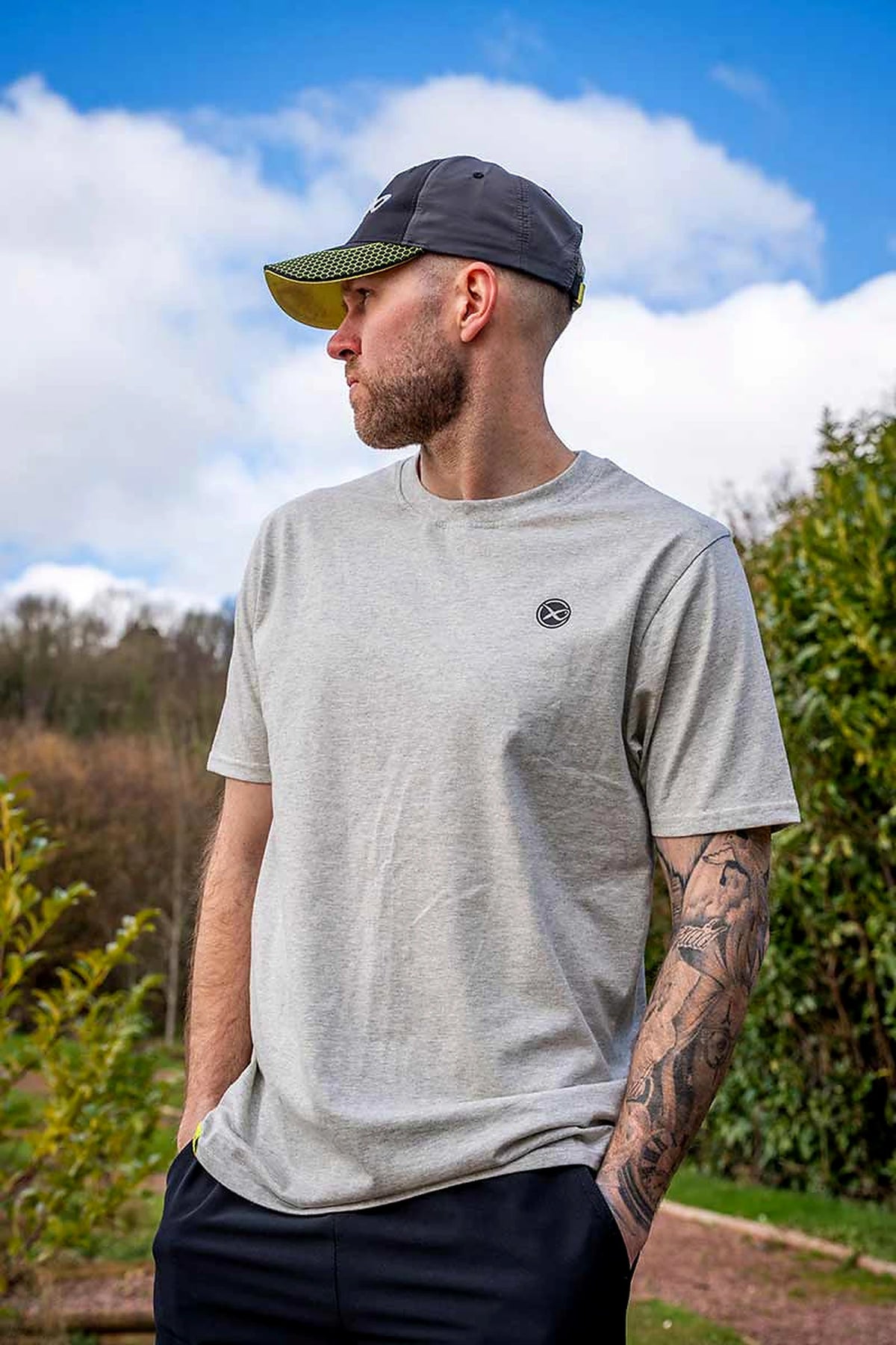 Matrix Grey Mini Logo T-shirt – buitenopname van het bovenlichaam van een model met pet, met zicht op borstlogo, mouwen en pasvorm