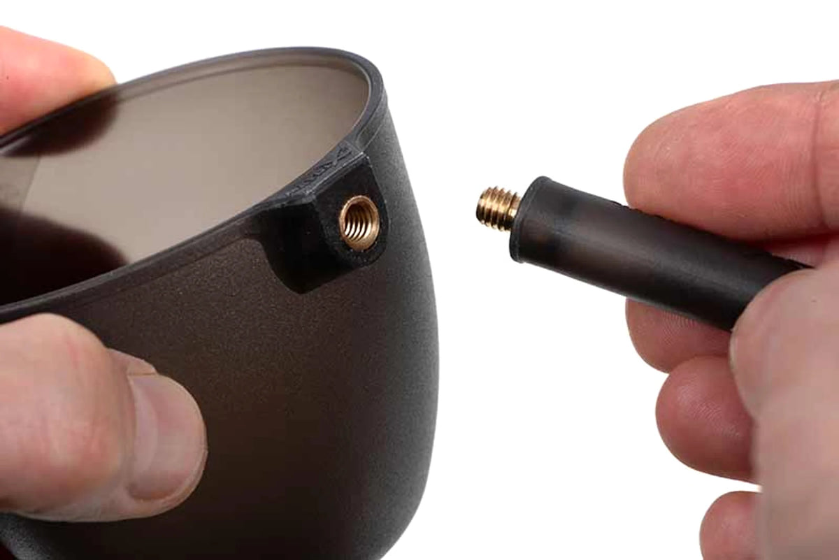 Messing binnendraad van een Matrix Groundbait Cup V2 naast de losse adapter, met beide handen zichtbaar