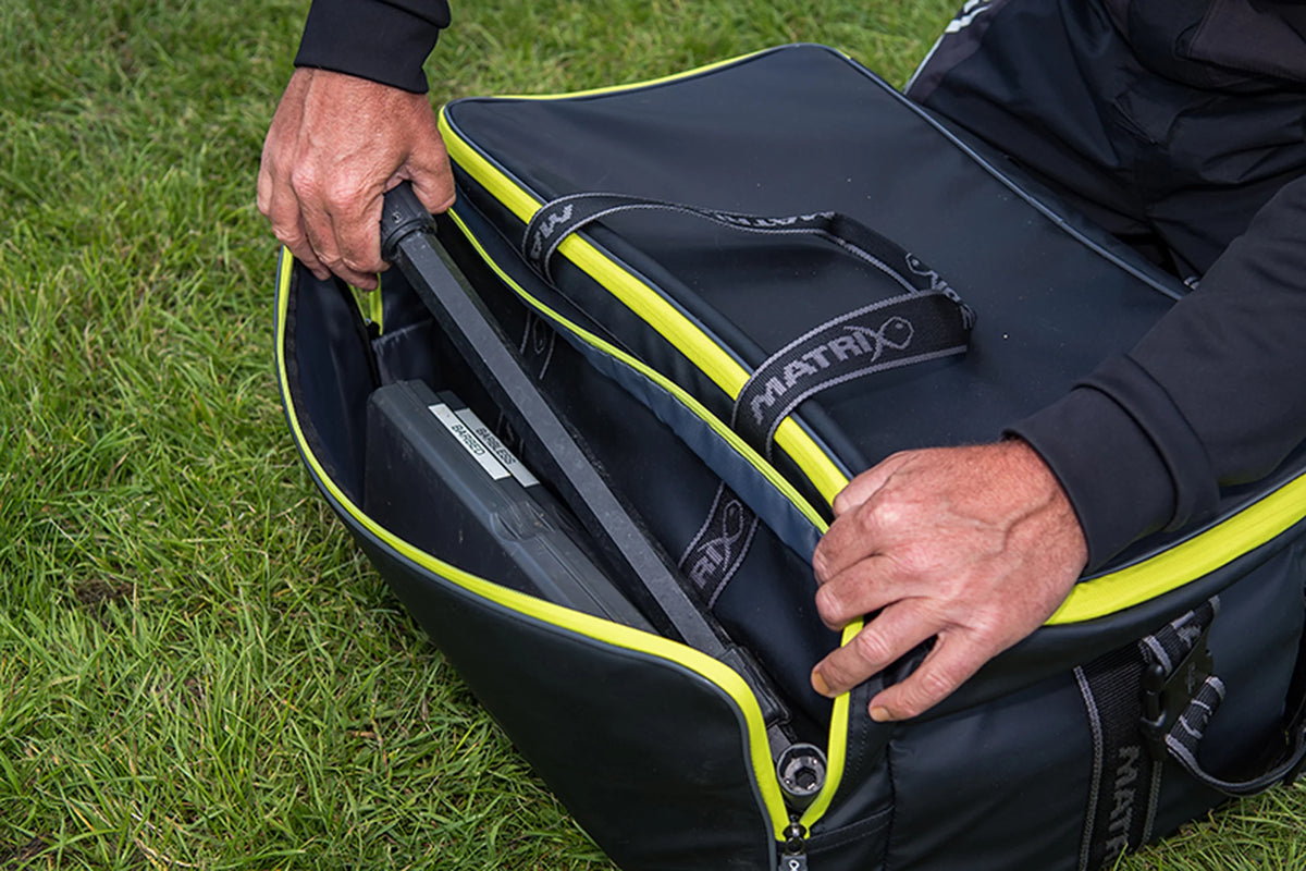 Matrix Horizon X Compact Carryall – visser neemt een onderlijnendoos uit het geopende buitenvak in het gras