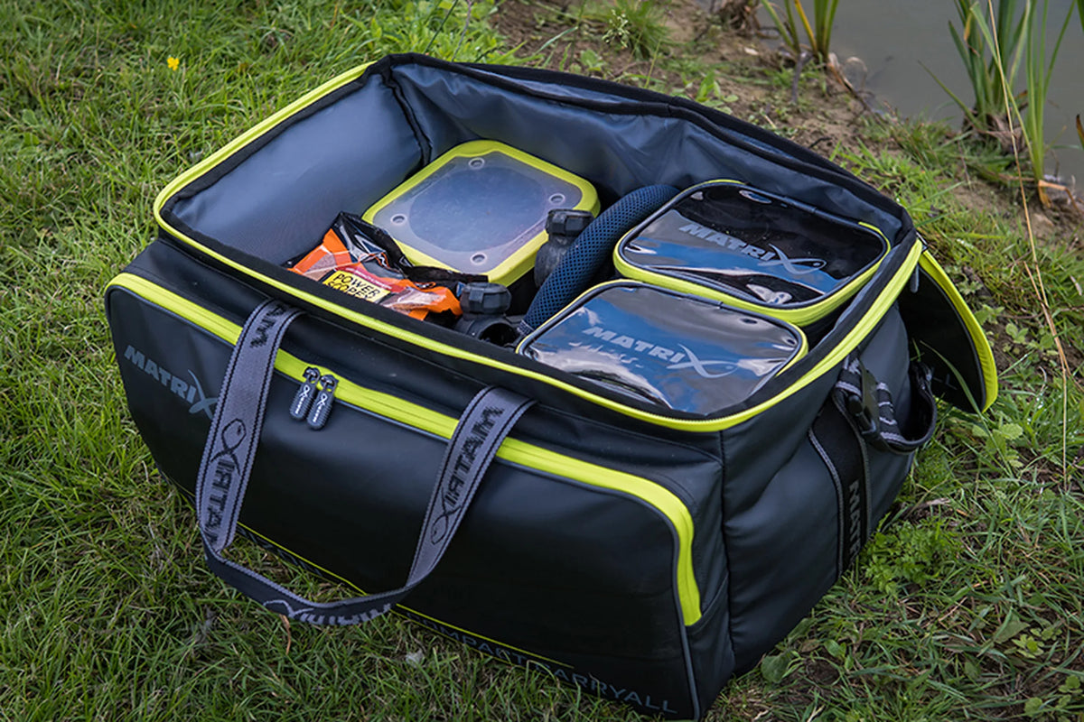 Matrix Horizon X Compact Carryall – geopend en gevuld hoofdvak met opbergtasjes en vismateriaal in het gras