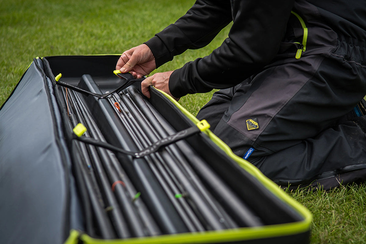 Matrix Horizon X Multi Pole Holdall – visser bedient de binnenriem boven de opgeborgen hengeldelen in het gras
