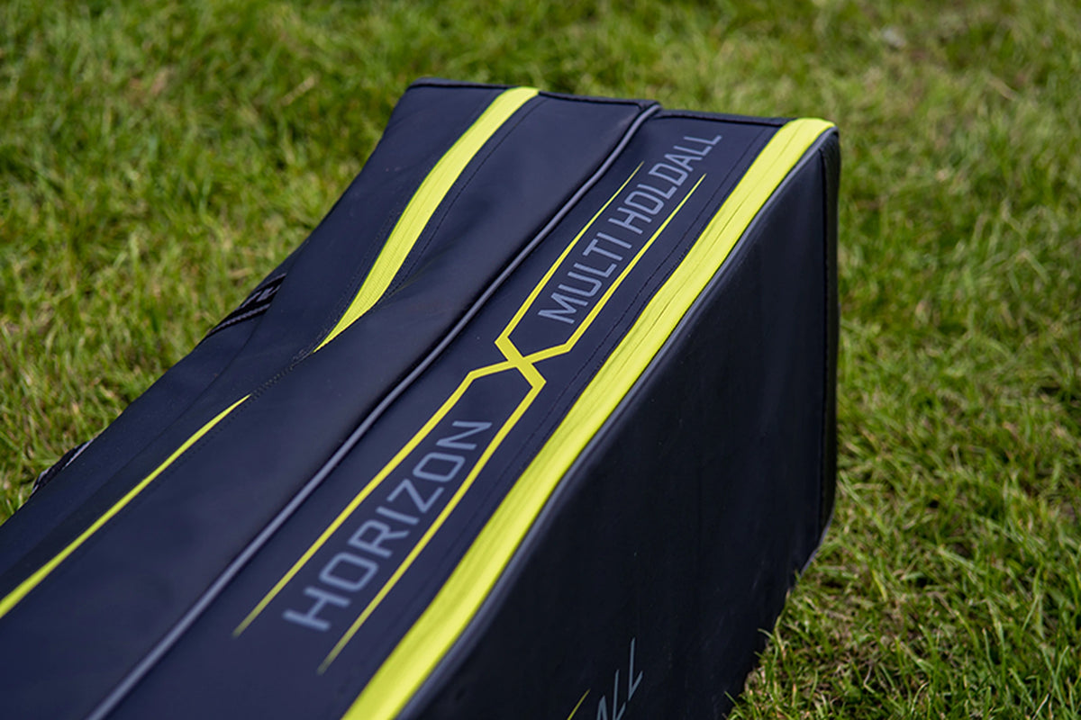Matrix Horizon X Multi Pole Holdall – detail van de Horizon X Multi Holdall-modelbedrukking naast de gele rits in het gras