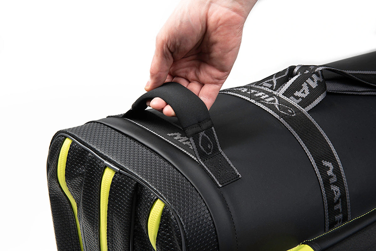Matrix Horizon X XL Rigid Rod Holdall 3-6 – hand om de bodemhandgreep naast de verstevigde bodem en drie gele ritsen