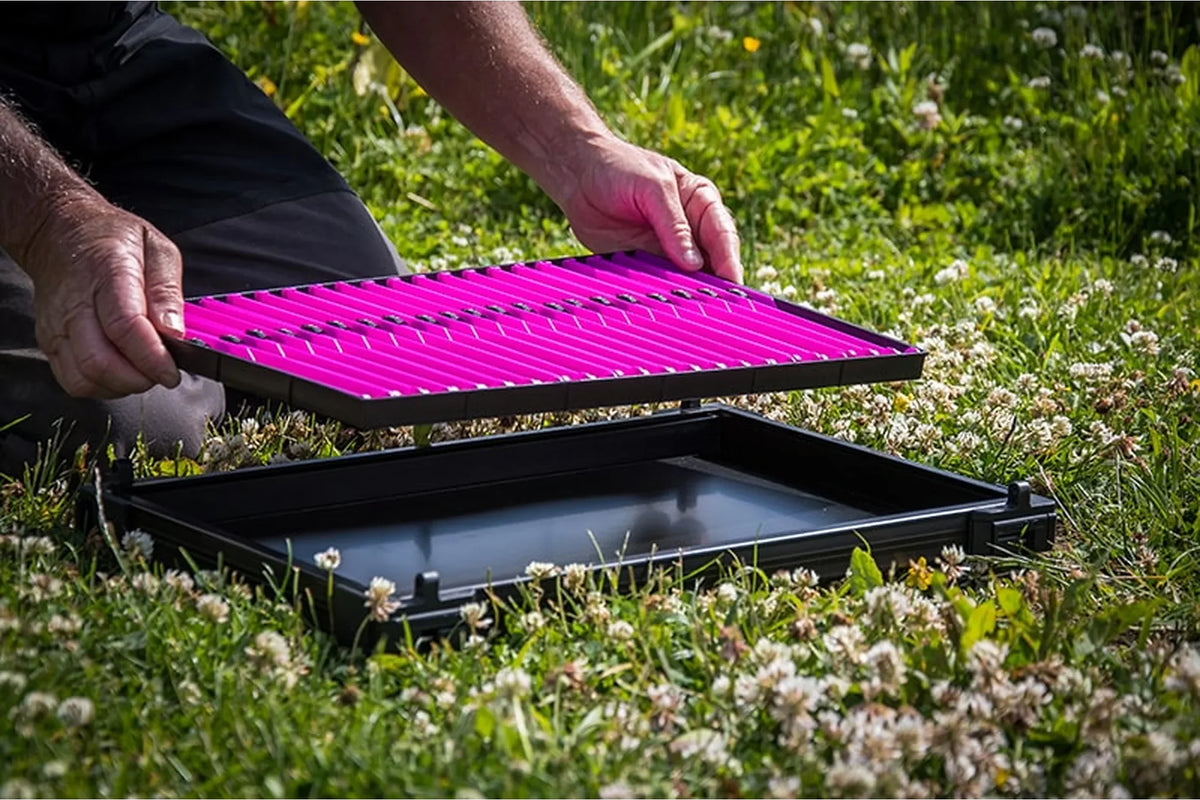 Matrix Pole Winders Loaded Tray – visser tilt de paarse lade-inzet met beide handen uit een zwarte traymodule op het gras