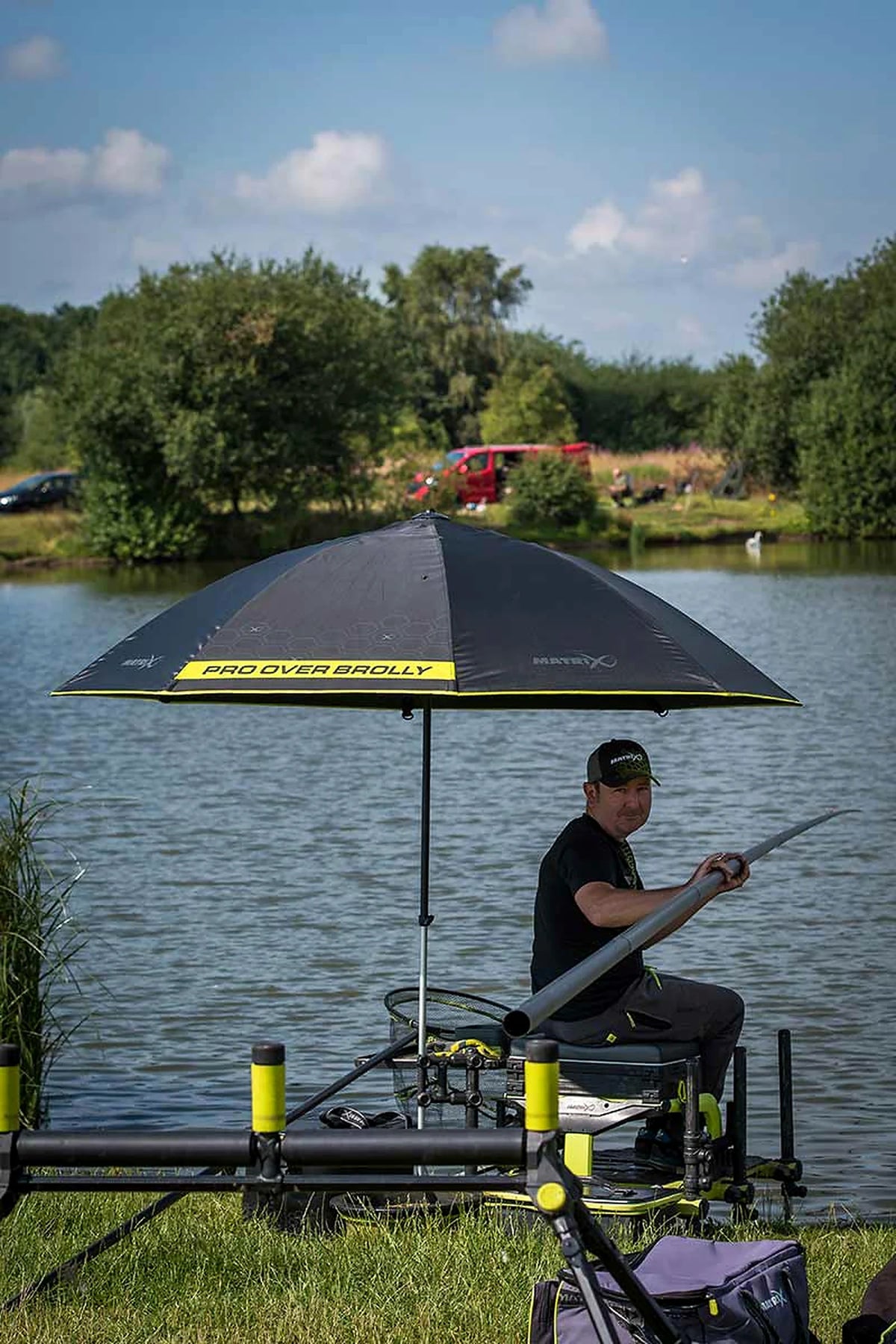 Matrix Pro Over Brolly 45 Inch – visser met vaste hengel onder de geopende paraplu op zijn visplek aan het water
