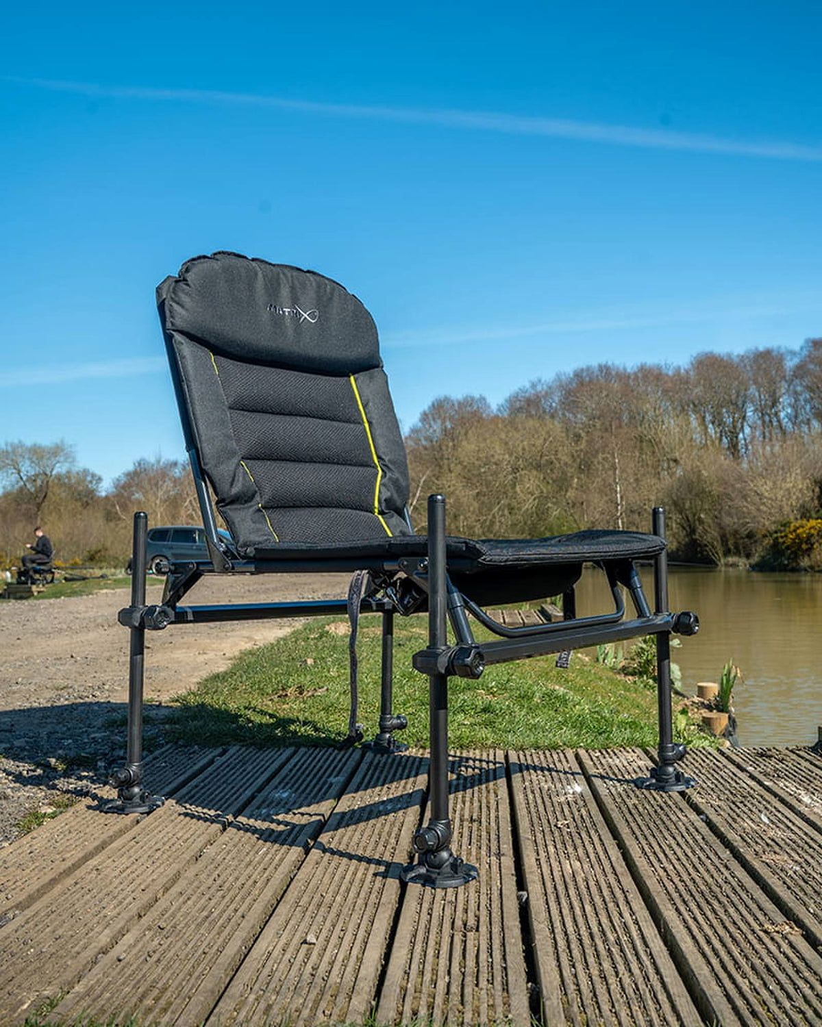 Matrix S25 Pro Accessory Chair met verstelbare poten opgesteld op een houten vissteiger aan de waterkant