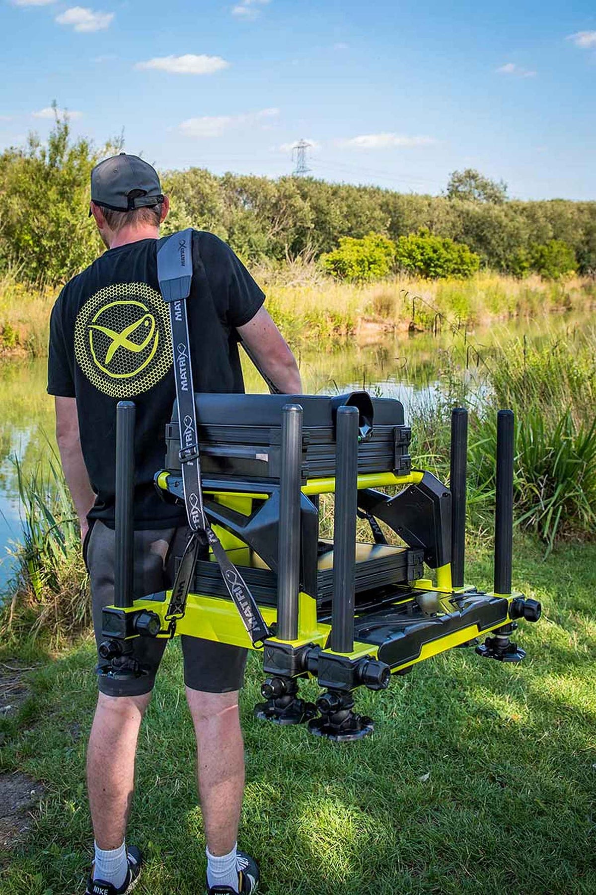 Matrix S36 Pro Lime-zitkist – visser draagt de volledige zitkist aan de schouderriem bij de vijver