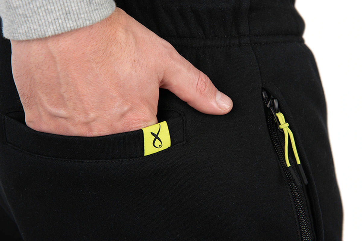Matrix Sherpa Joggers – hand in de achterzak met limegroen Matrix-label, naast een zwarte rits met limegroen trekkoord