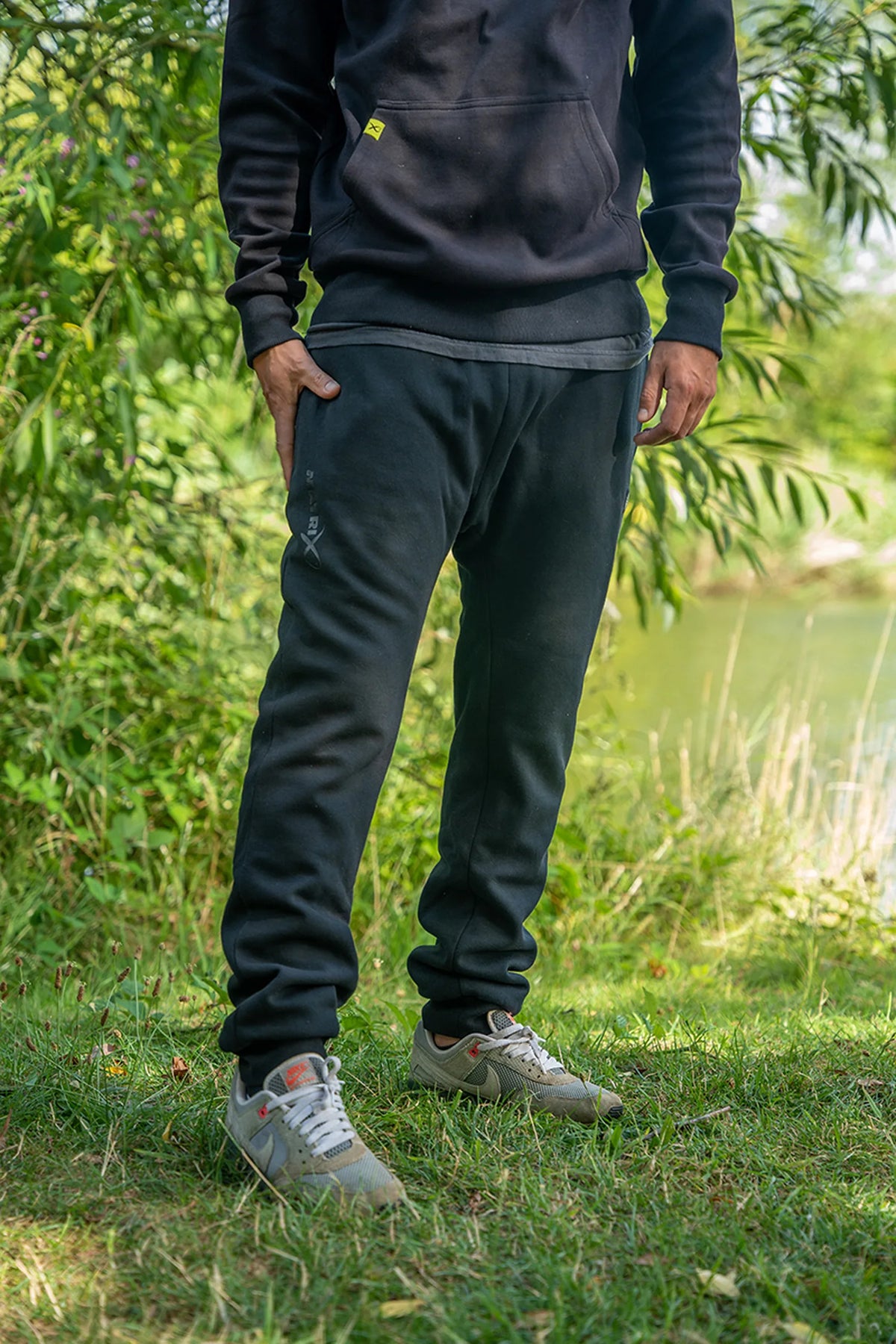 Matrix Sherpa Joggers – zwarte joggingbroek gedragen door een staand model op het gras aan de waterkant
