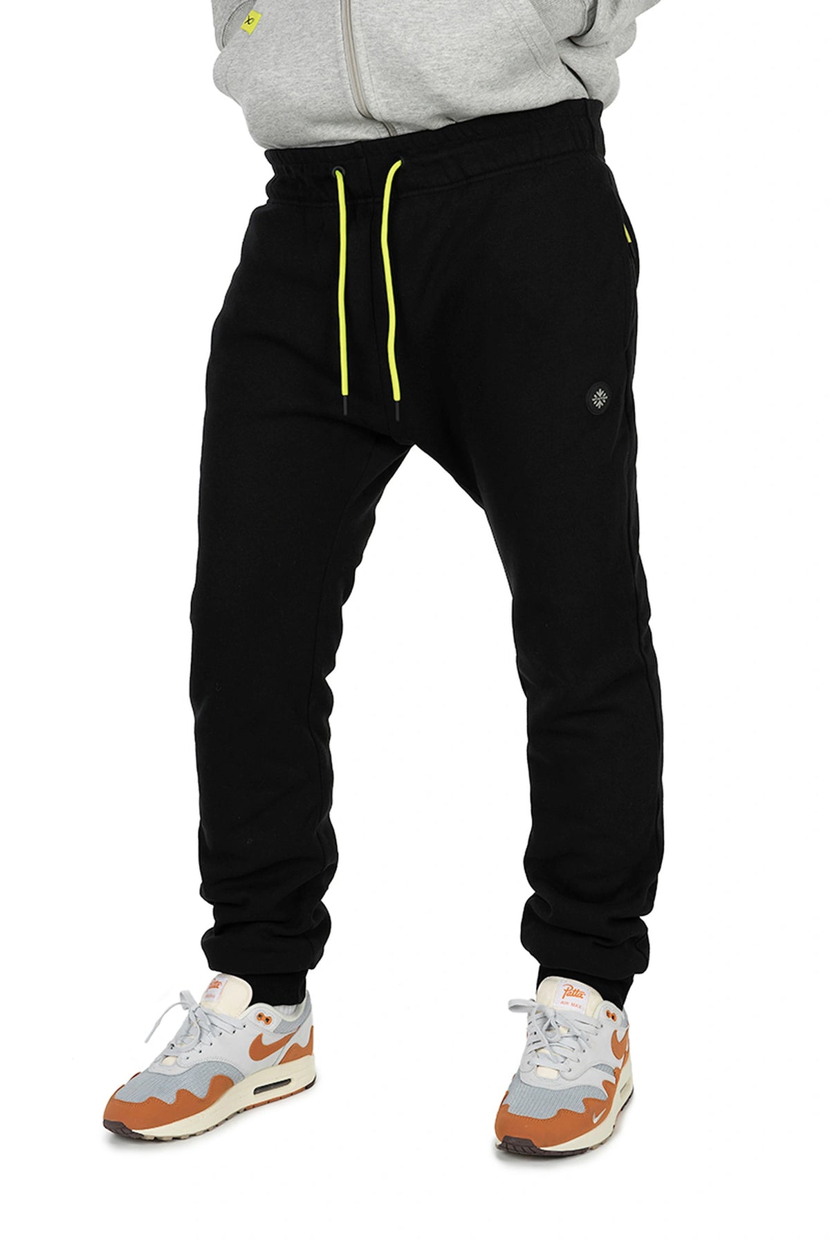 Matrix Sherpa Joggers – vooraanzicht van de zwarte joggingbroek op model, met limegroene trekkoorden en ronde badge