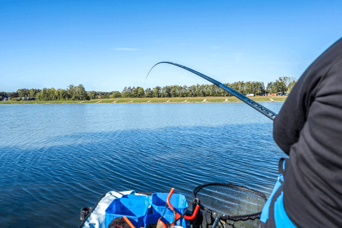 Preston Edge Monster Margin 11m – gebogen hengel boven het water, gezien langs de schouder van de visser
