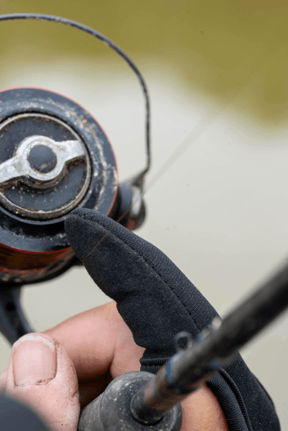 Preston Extremity Finger Stall tijdens het vissen, met beschermde vingertop naast de molenspoel en hengel