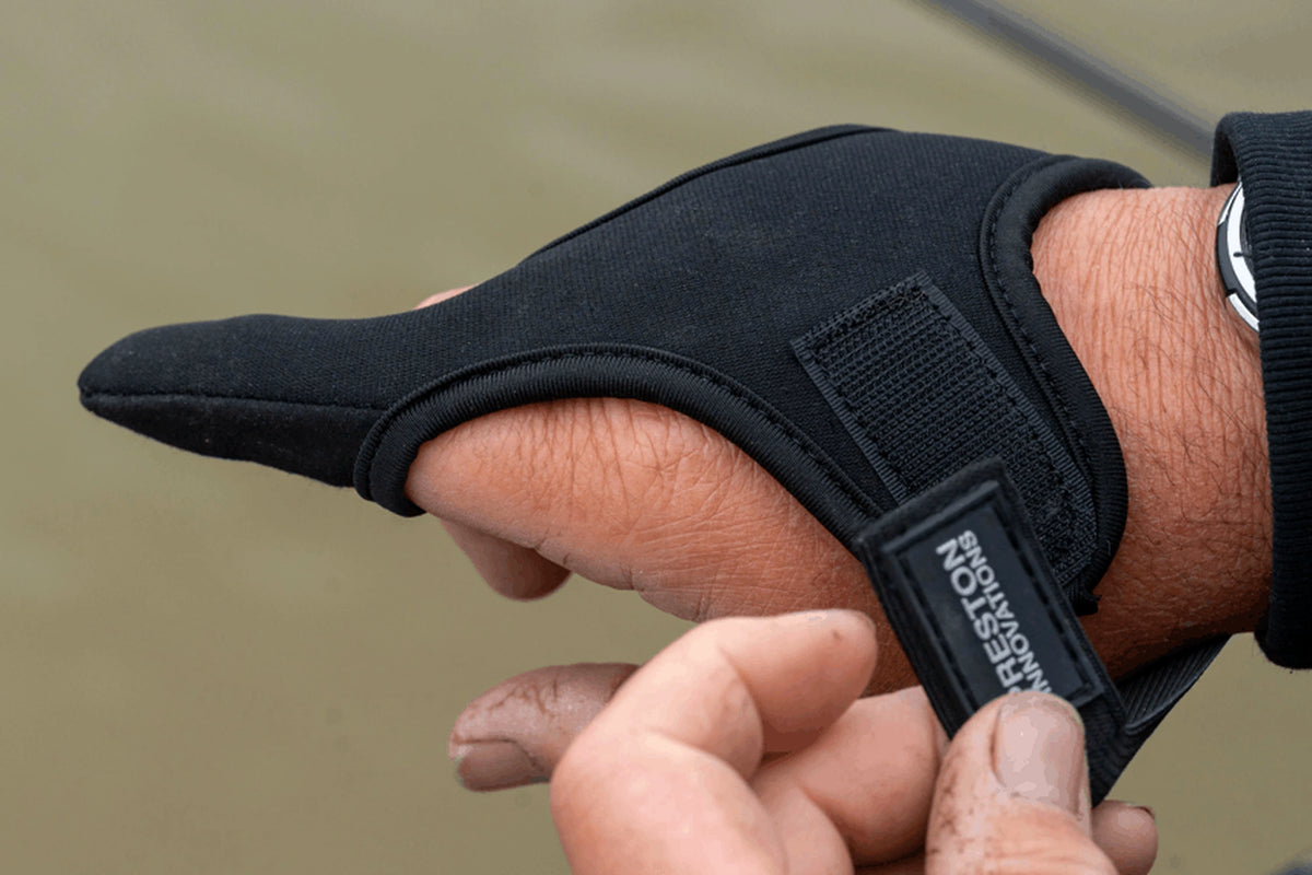 Preston Extremity Finger Stall op de hand terwijl de verstelbare klittenband-polssluiting met Preston Innovations-etiket wordt vastgemaakt