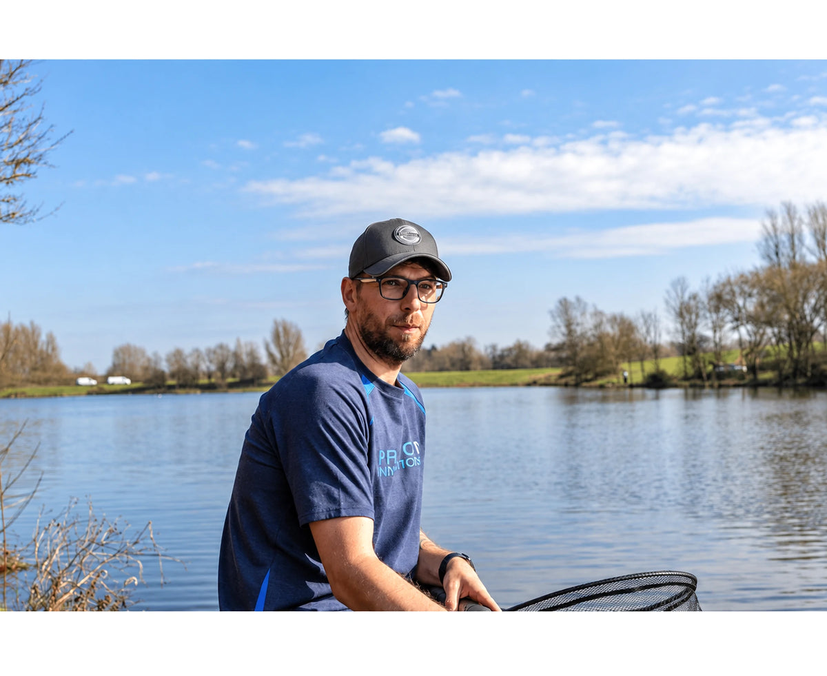 Visser draagt de Preston Grey Granite Cap zittend naast het water