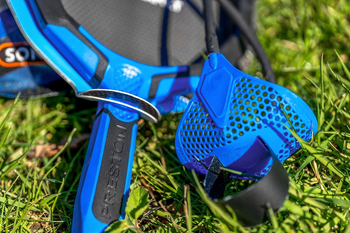 Blauwe geperforeerde pouch, zwarte trekband en Preston-handvat op het gras