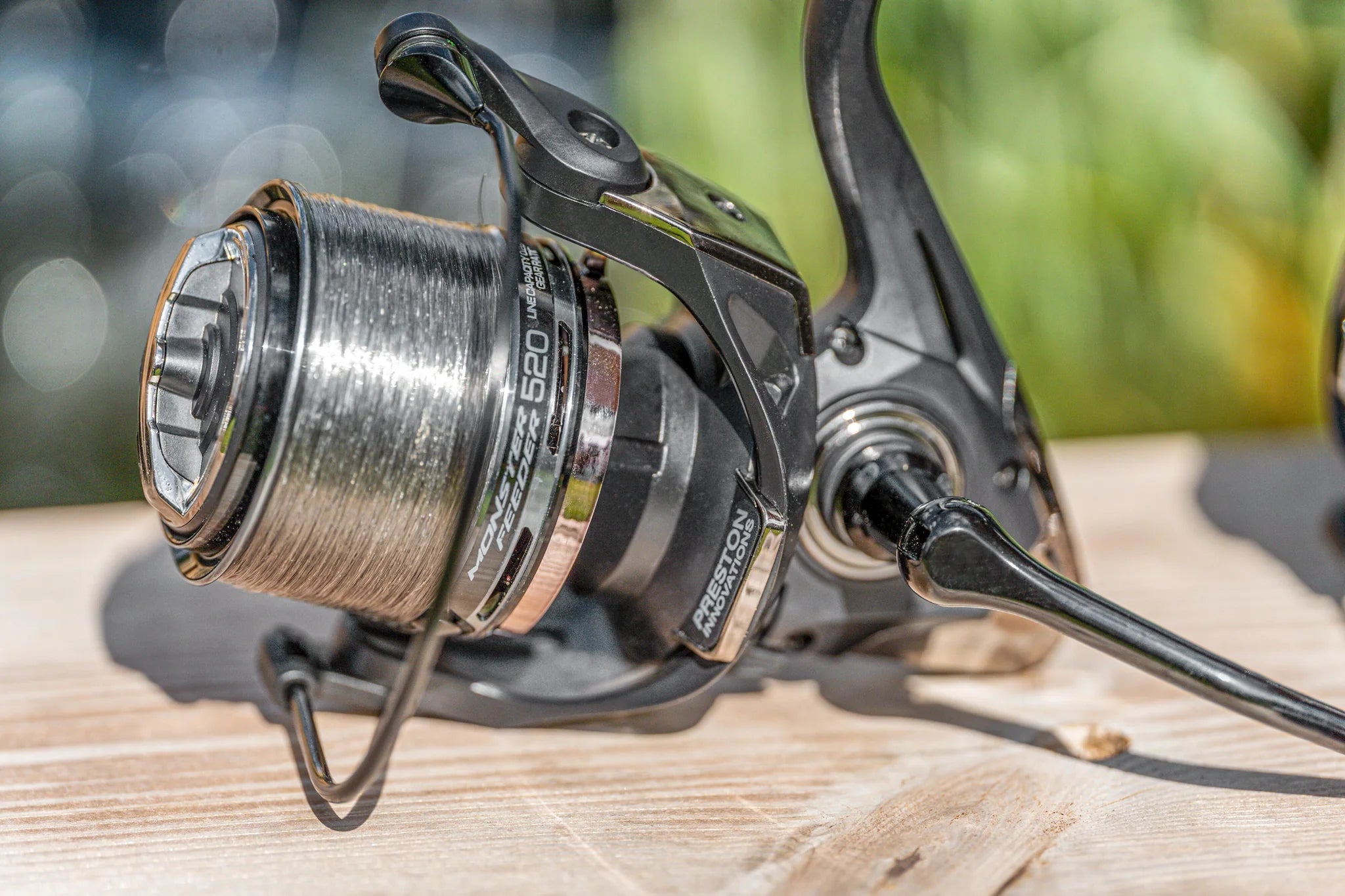 Preston Monster Feeder Reel met opgespoelde lijn op houten ondergrond