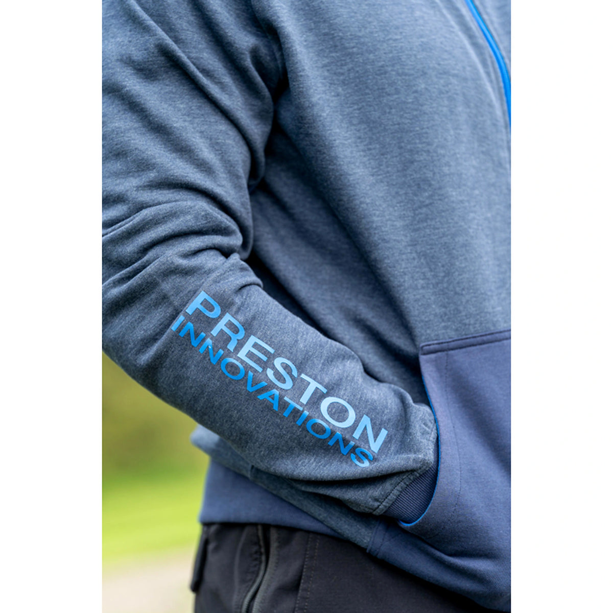 Preston Navy Tide Zip Hoodie – detail van het blauwe Preston Innovations-mouwlogo, de manchet en de buidelzak