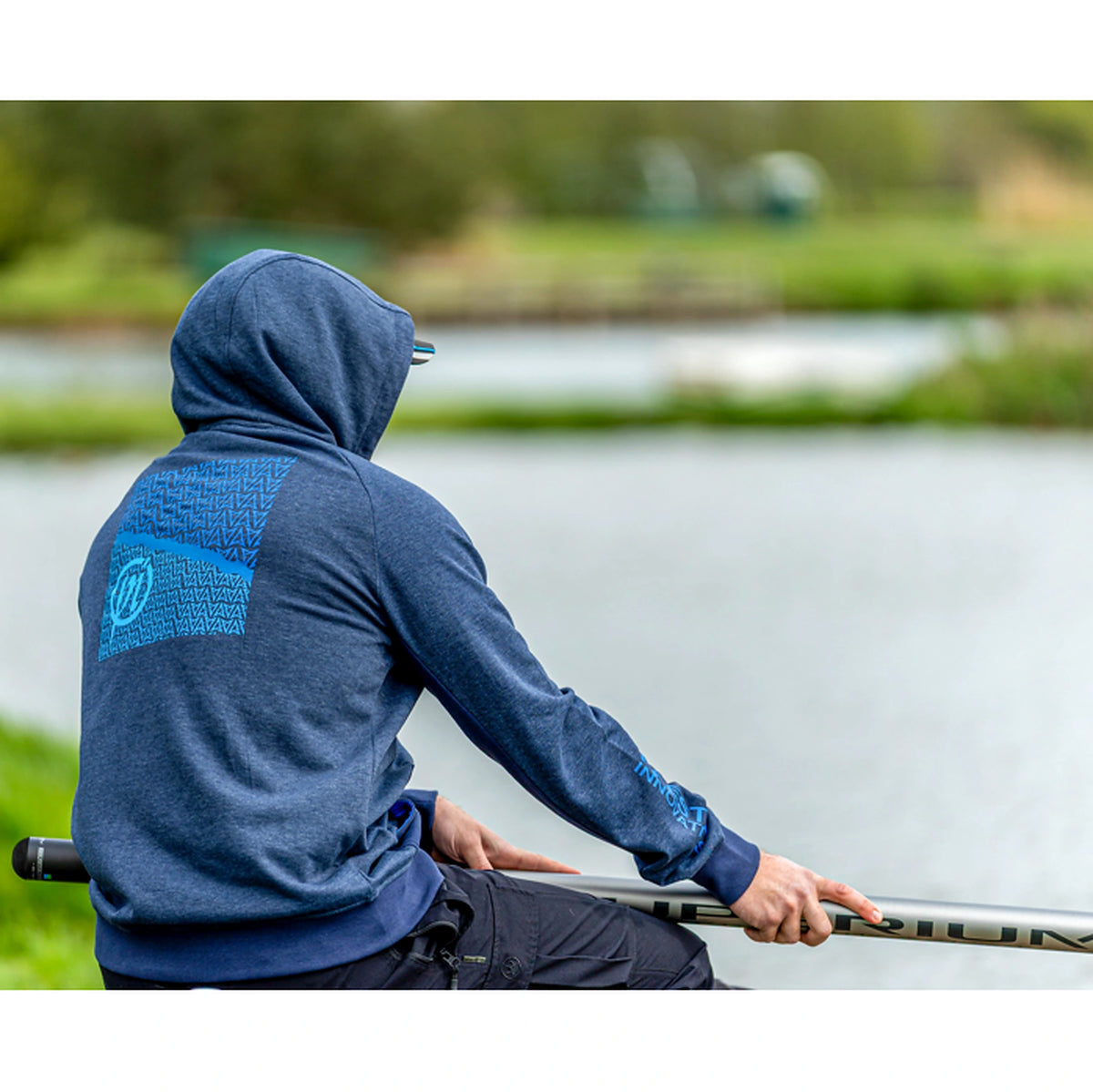 Preston Navy Tide Zip Hoodie – gedragen tijdens het vissen, met opgezette capuchon en de blauwe rugopdruk zichtbaar