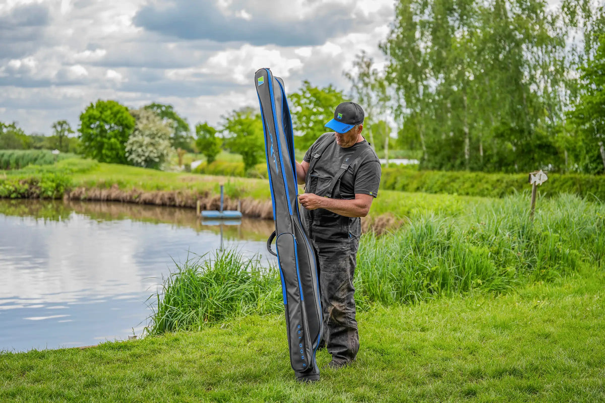 Visser opent de blauwe ritssluiting van het rechtopstaande Preston Supera X 2 Rod 195-foedraal aan de waterkant