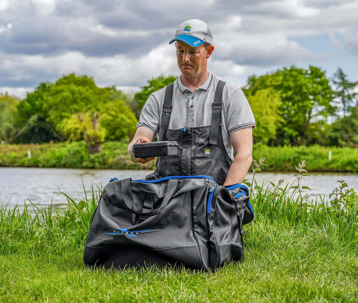 Preston Supera X Carryall draagtas met een visser die materiaal opbergt aan de waterkant