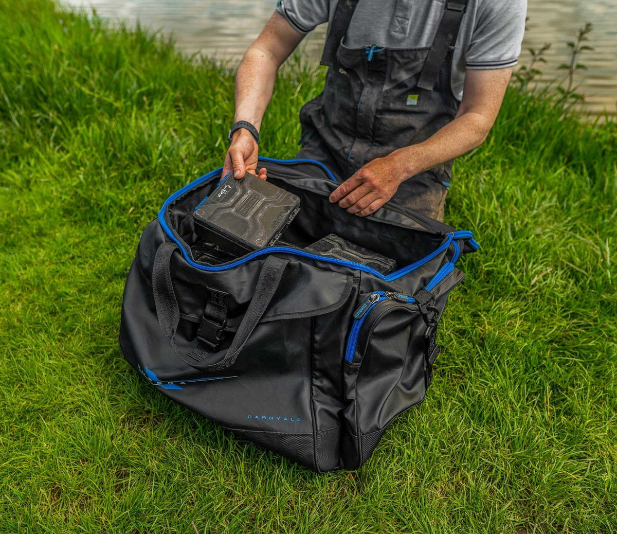 Preston Supera X Carryall met geopend hoofdvak terwijl een visser materiaal in de tas pakt
