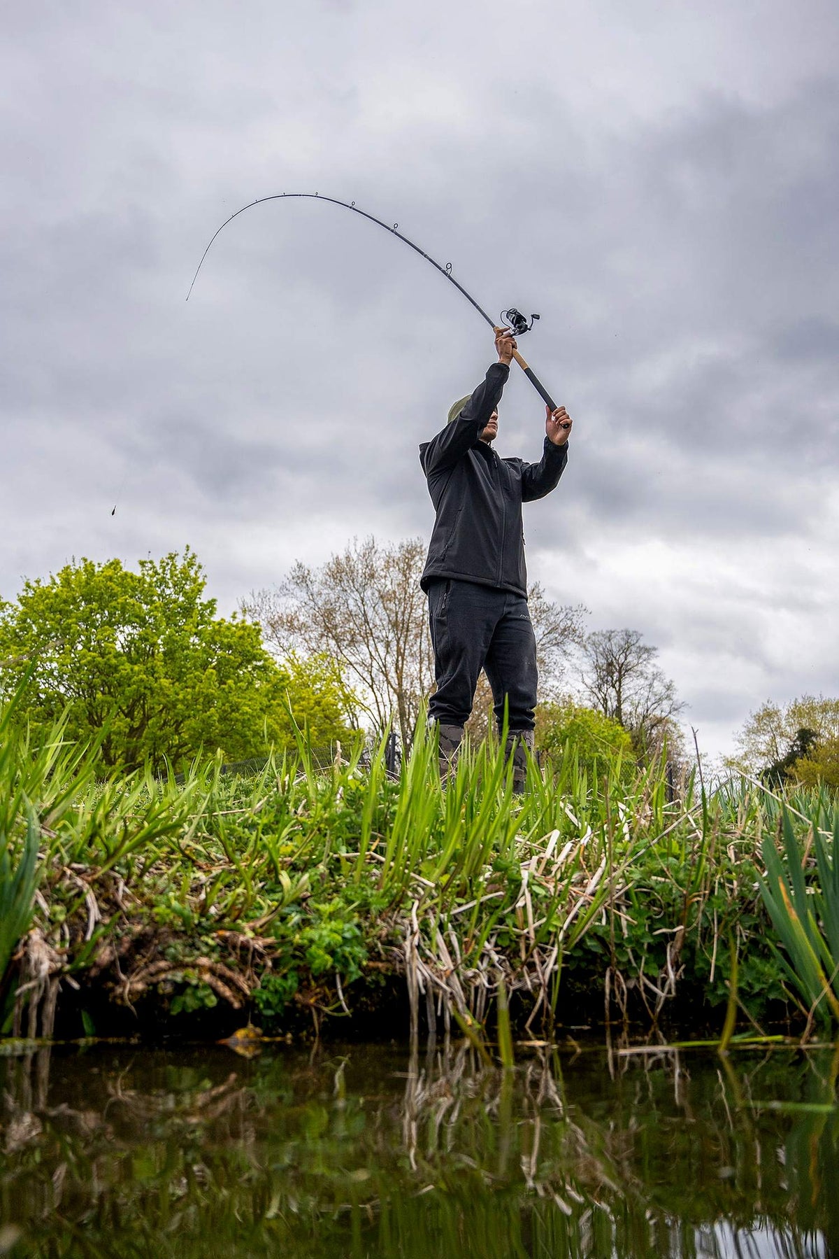 Zebco Feeder Combo – visser werpt met de gebogen feederhengel vanaf de begroeide waterkant