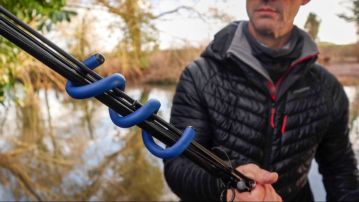 Zebco Trophy Rod Wraps – blauwe spiraalbanden rond een hengelbundel die een visser aan de waterkant vasthoudt