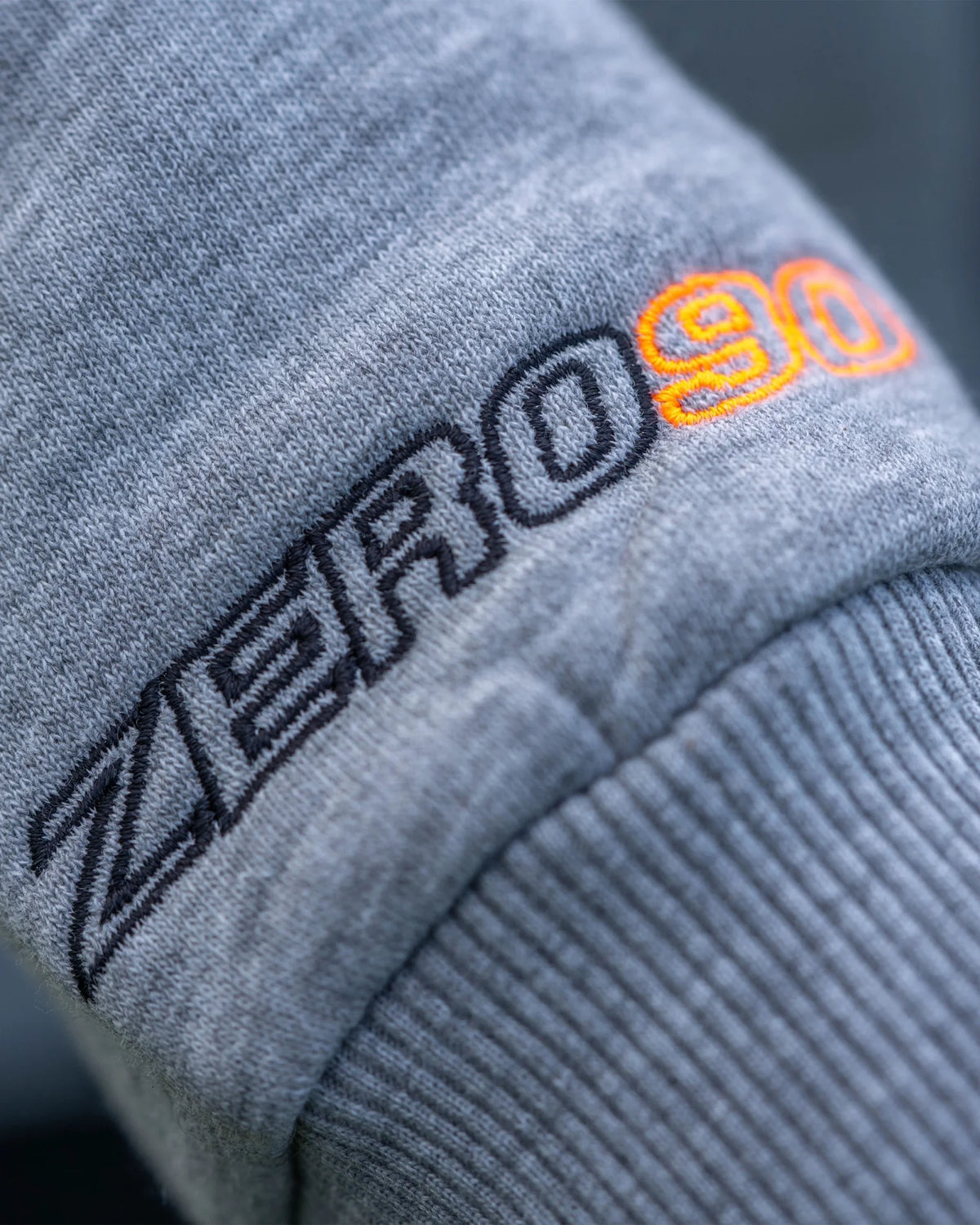 Guru Aventus Hoodie Grey, detail van zwart en oranje mouwborduurwerk en geribde boord