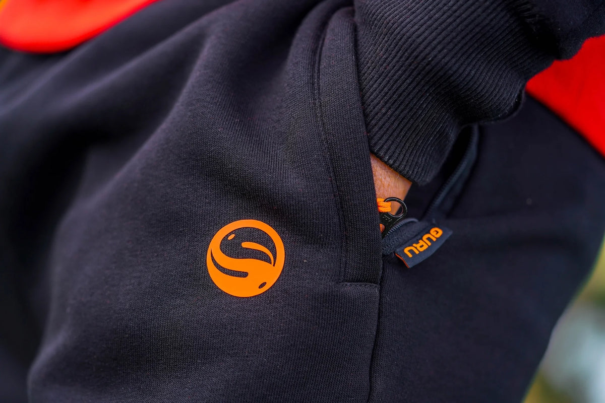 Guru Black Joggers – detail van het oranje Guru-embleem op de broekspijp