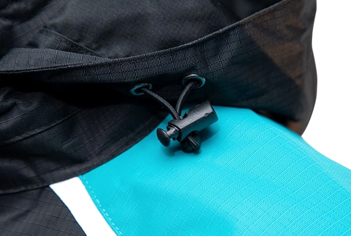 Drennan 25K WP Jacket: verstelkoord met koordstopper onder de zwarte capuchon, boven het turquoise schouderpaneel