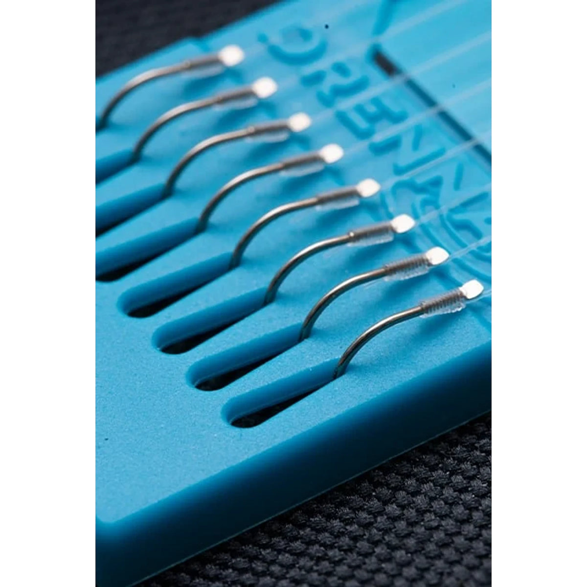 Drennan Margin Carp Barbless Hooklengths – detail van acht haken op blauwe Hook Plate