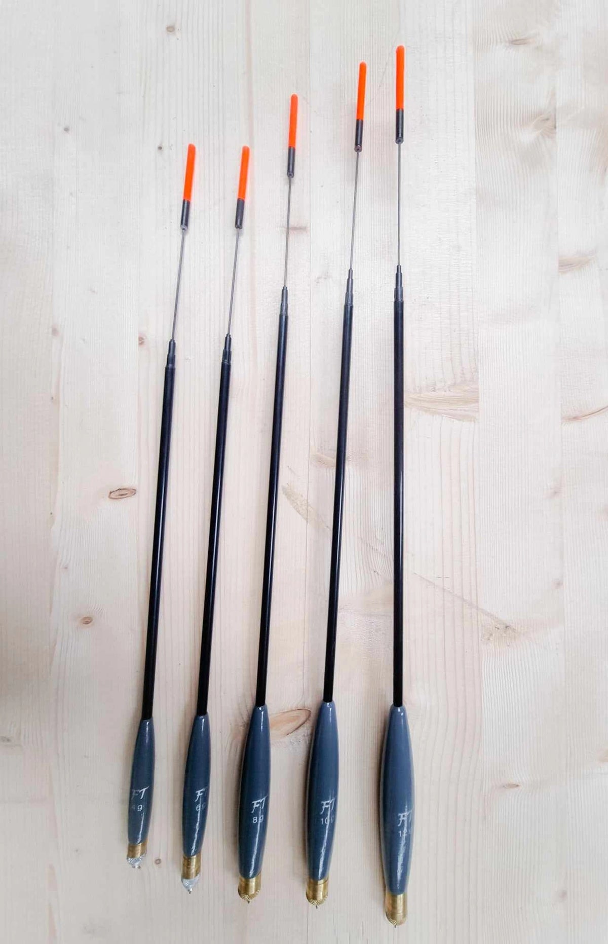 Vijf Fishing Things Match 3-dobbers met oranje antennes op een houten ondergrond
